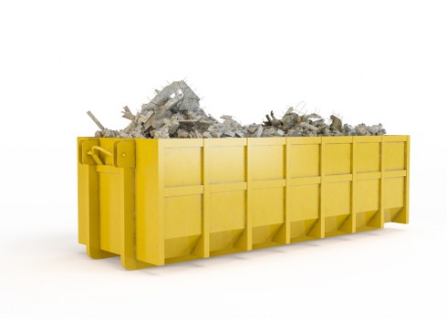 A large, rectangular skip with bright yellow panels and reinforced edges, positioned on a clean, white surface. The skip is filled with a substantial load of mixed construction debris, including broken bricks, concrete chunks, and rubble, which spill slightly over the top edges. The debris displays rough textures, with earthy grey and tan tones contrasting against the smooth, glossy finish of the skip. In the background, there is a neutral, uncluttered environment, emphasizing the skip's purpose for commercial waste collection. The image reflects a typical scene for waste removal services offered by Commercial Waste Brompton, situated near Brompton or the surrounding postcode area, highlighting their capacity for handling construction or renovation refuse. The scene is well-lit, with even lighting that highlights the textures of the debris and the vibrant colour of the skip, aligning with professional rubbish removal operations.